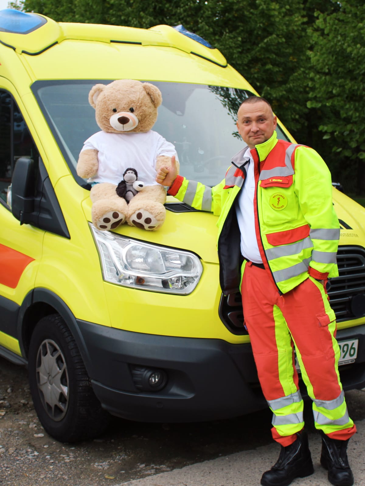 Tom Mentler daumen-hoch mit dem Teddybären im Rettungsfahrzeug