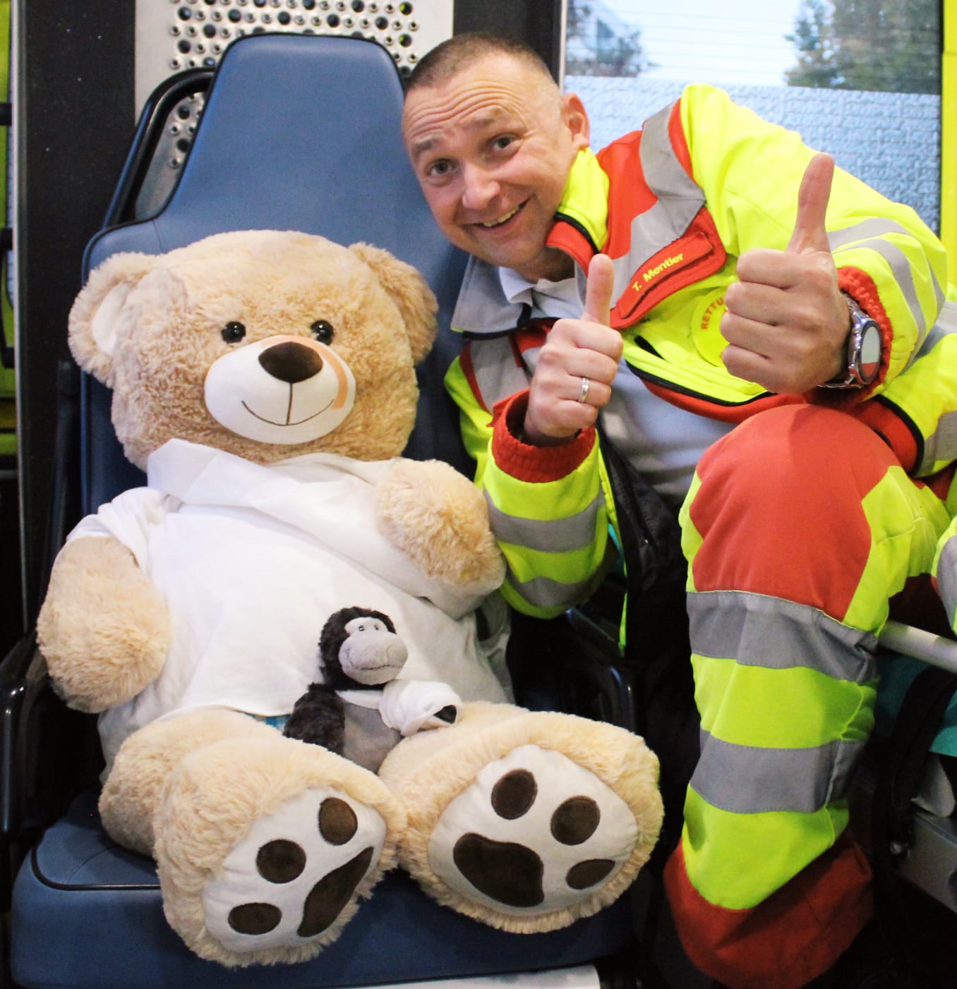 Tom Mentler als Rettungssanitäter neben dem Krankenwagen mit dem Maskottchen-Teddy